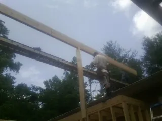 Carpenter setting a ridge beam over a new addition frame — Ice Dam Removal by Roofing Brothers in Noti