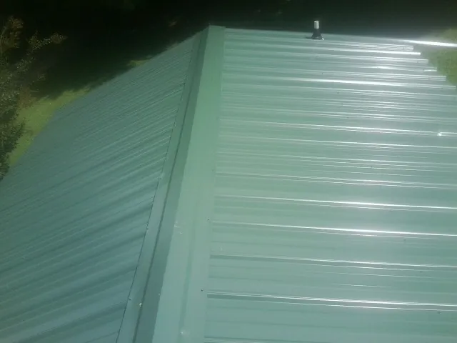 New green metal panels meeting at the ridge of a roof — Flat Roof Repair work by our crew in Noti