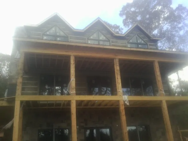 Dormers and porch framing on a large log home under construction — Roof Coating work by our crew in Noti