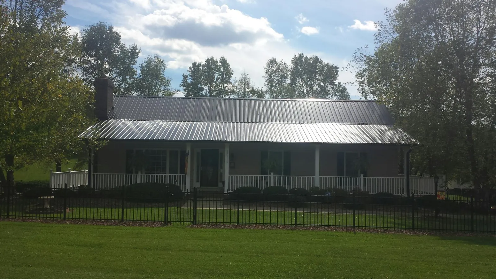 Gray metal roof on a brick ranch with a full width front porch — Gutter Guard Installation work by our crew in Noti