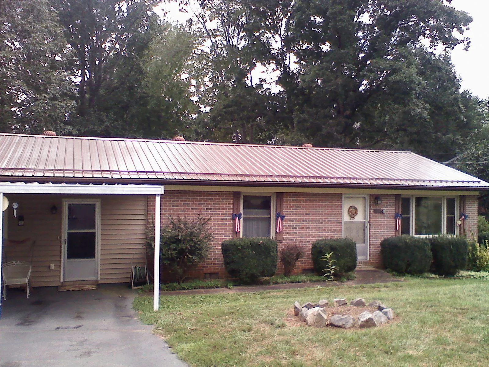 Bronze metal roof and carport on a brick ranch home — Roof Repair work by our crew in Noti